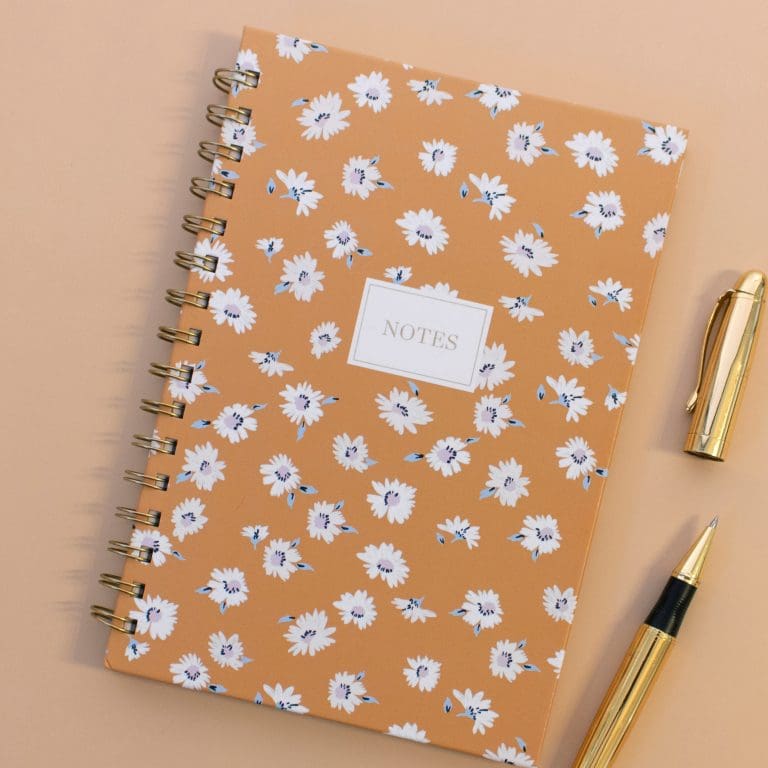 peach colored spiraled notebook with pen image