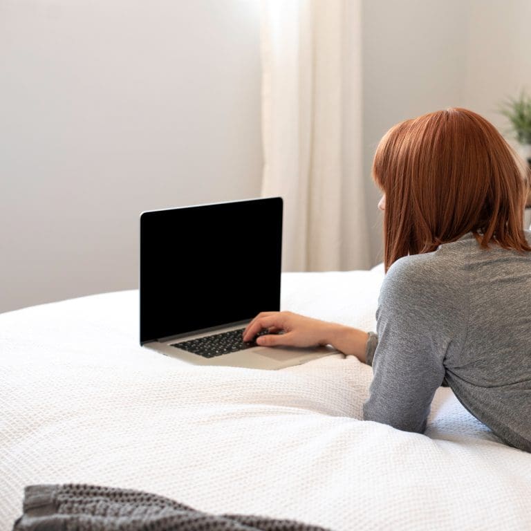 woman laying on bed using laptop image