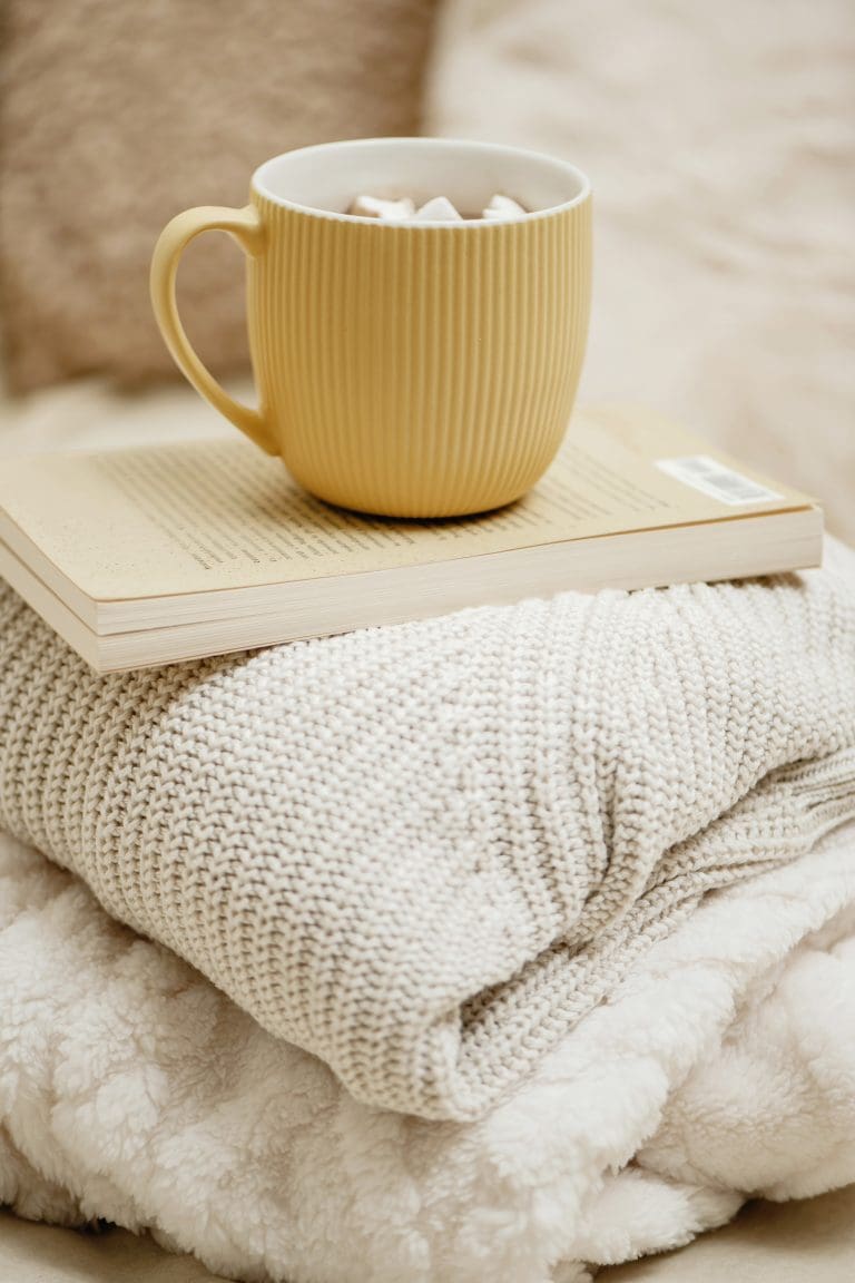 Cup of Cocoa atop a book atop a blanket